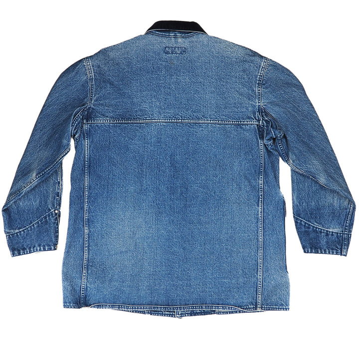 The back view of a blue denim jacket with long sleeves, a pointed collar, and a straight hem, shown on a plain white background.