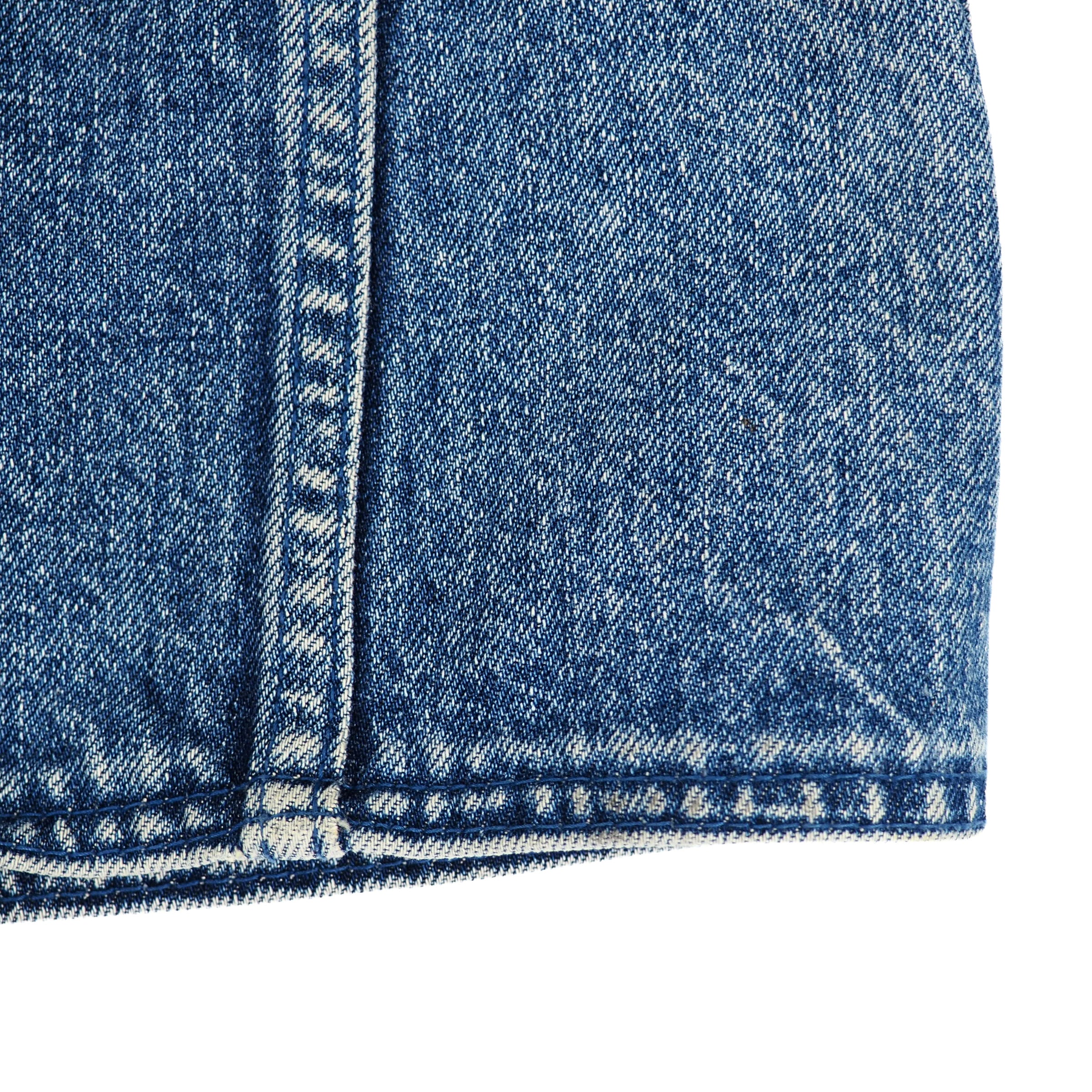 Close-up detail of blue denim fabric with white contrast stitching and a frayed hem on a white background.
