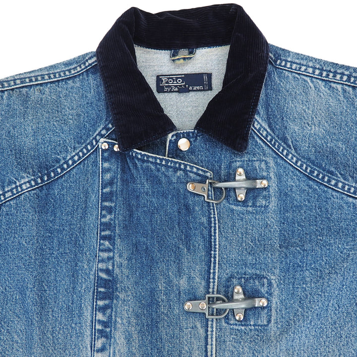 Close-up of a blue denim jacket with a dark navy corduroy collar and silver toggle closures, shown on a white background. The inner neck label reads Polo.