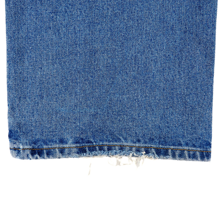 Close-up of blue denim jean pant leg with frayed cuff on a white background