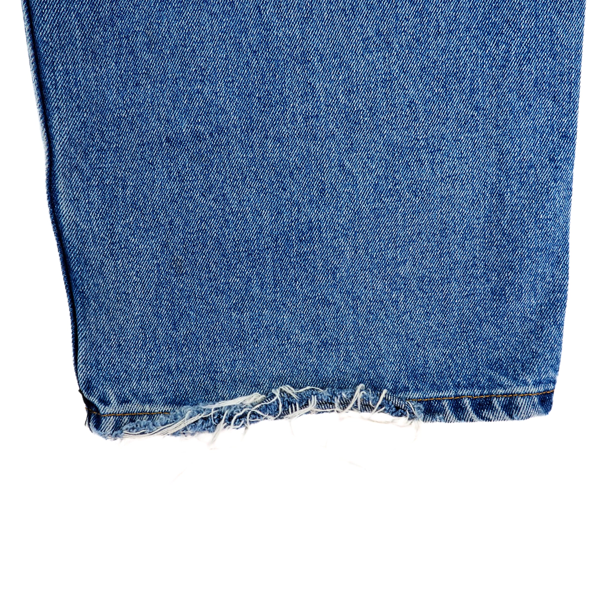 Close-up of blue denim jean pant leg ankle cuff with frayed edges on a white background