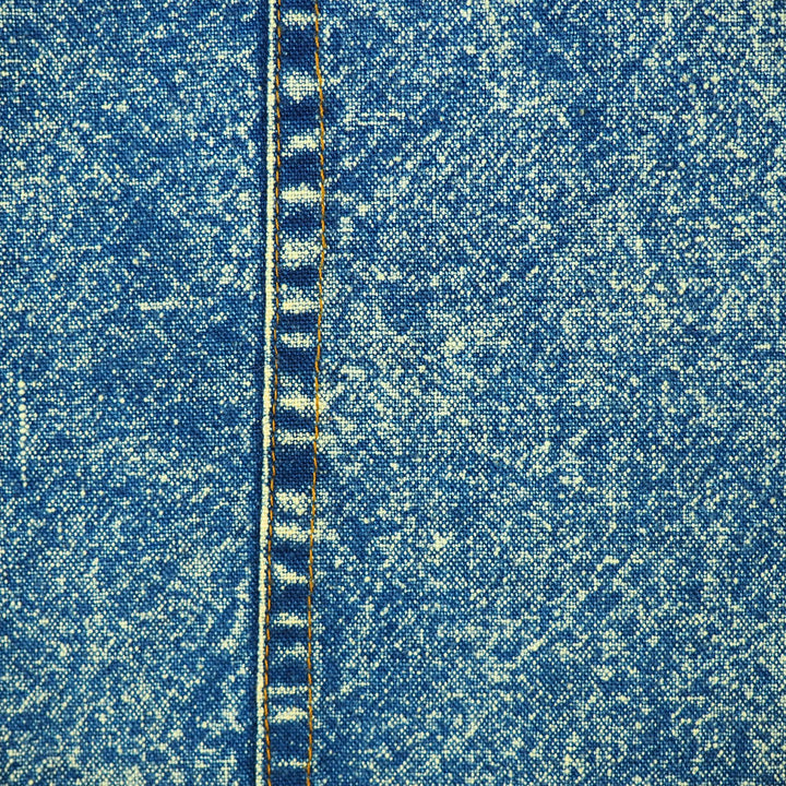 Close-up of blue acid wash denim fabric and seam with orange stitching