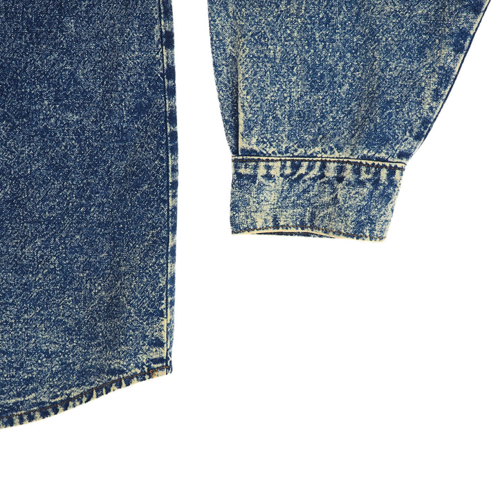 Close-up of blue denim shirt sleeve cuff and tail with a white background