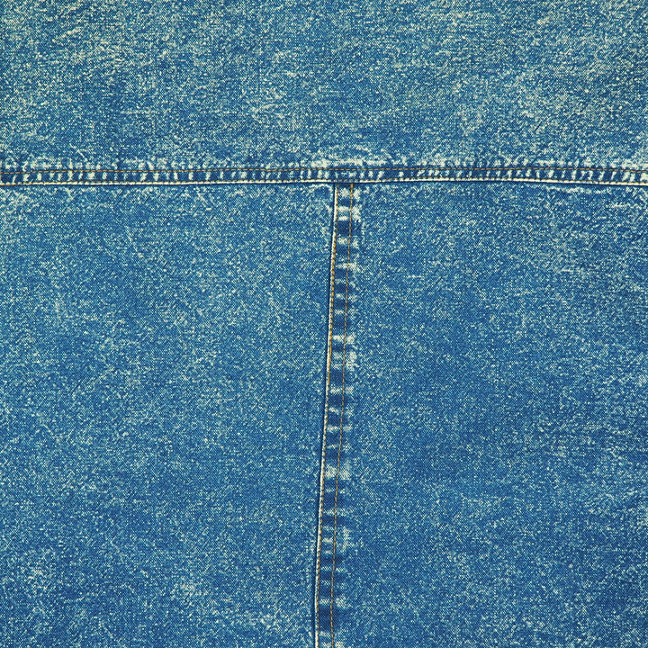 Close-up of back of an acid wash blue denim shirt with a visible T seam with orange stitching.
