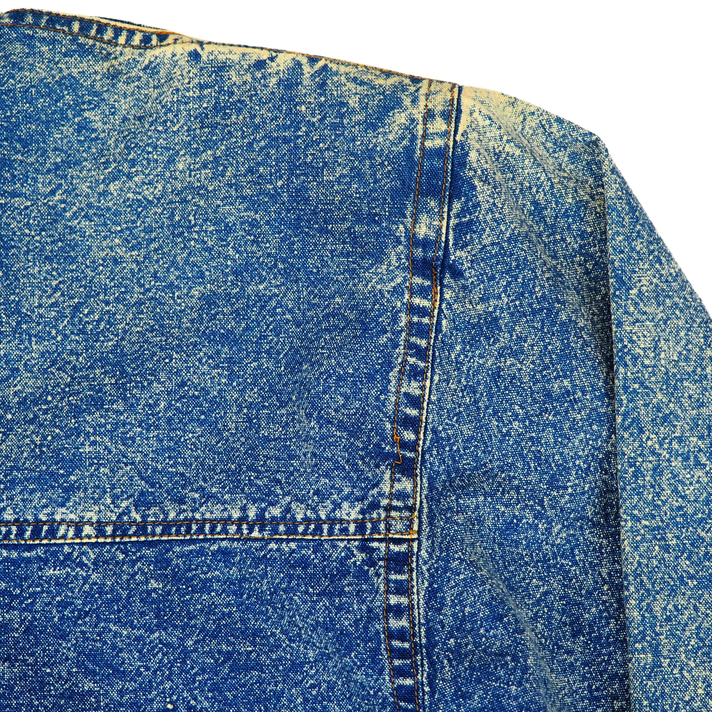 Close-up of blue acid wash denim shirt shoulder detail with a focus on patina, texture and stitching.