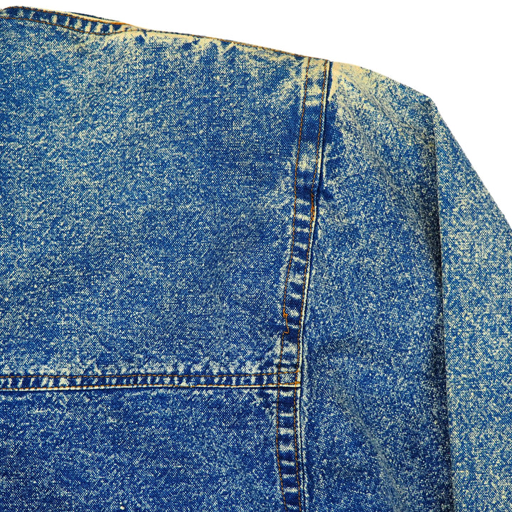 Close-up of blue acid wash denim shirt shoulder detail with a focus on patina, texture and stitching.