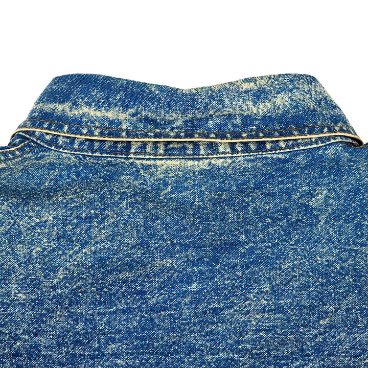 Close-up focusing on patina and texture of a vintage blue acid wash denim shirt collar with orange stitching on a white background.