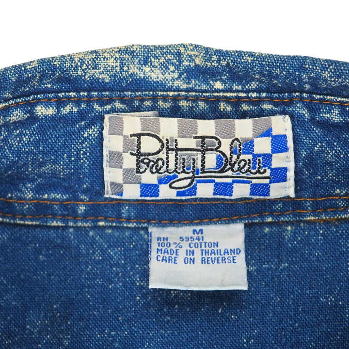 Close-up of a blue denim shirt with 'Pretty Blue' label branding on a white background.