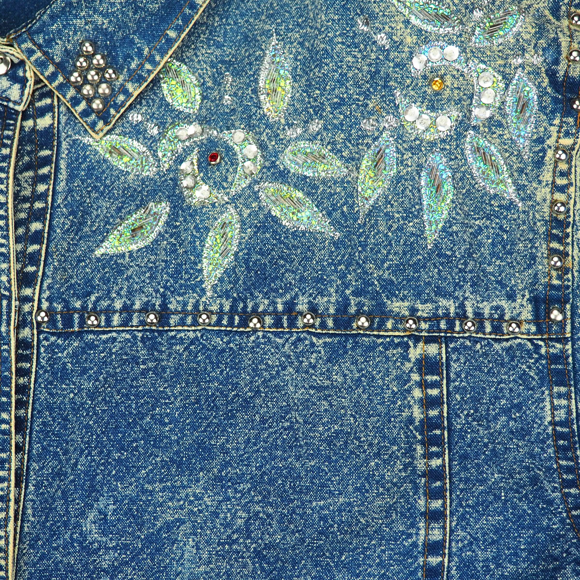 Close-up of a blue acid wash denim shirt with floral embroidery and rhinestone beading