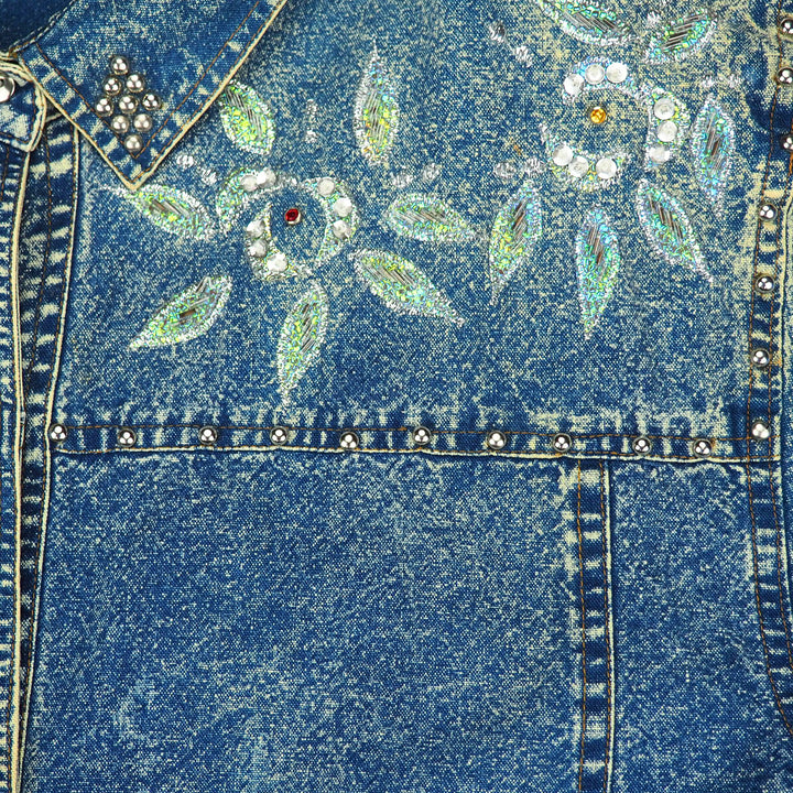 Close-up of a blue acid wash denim shirt with floral embroidery and rhinestone beading
