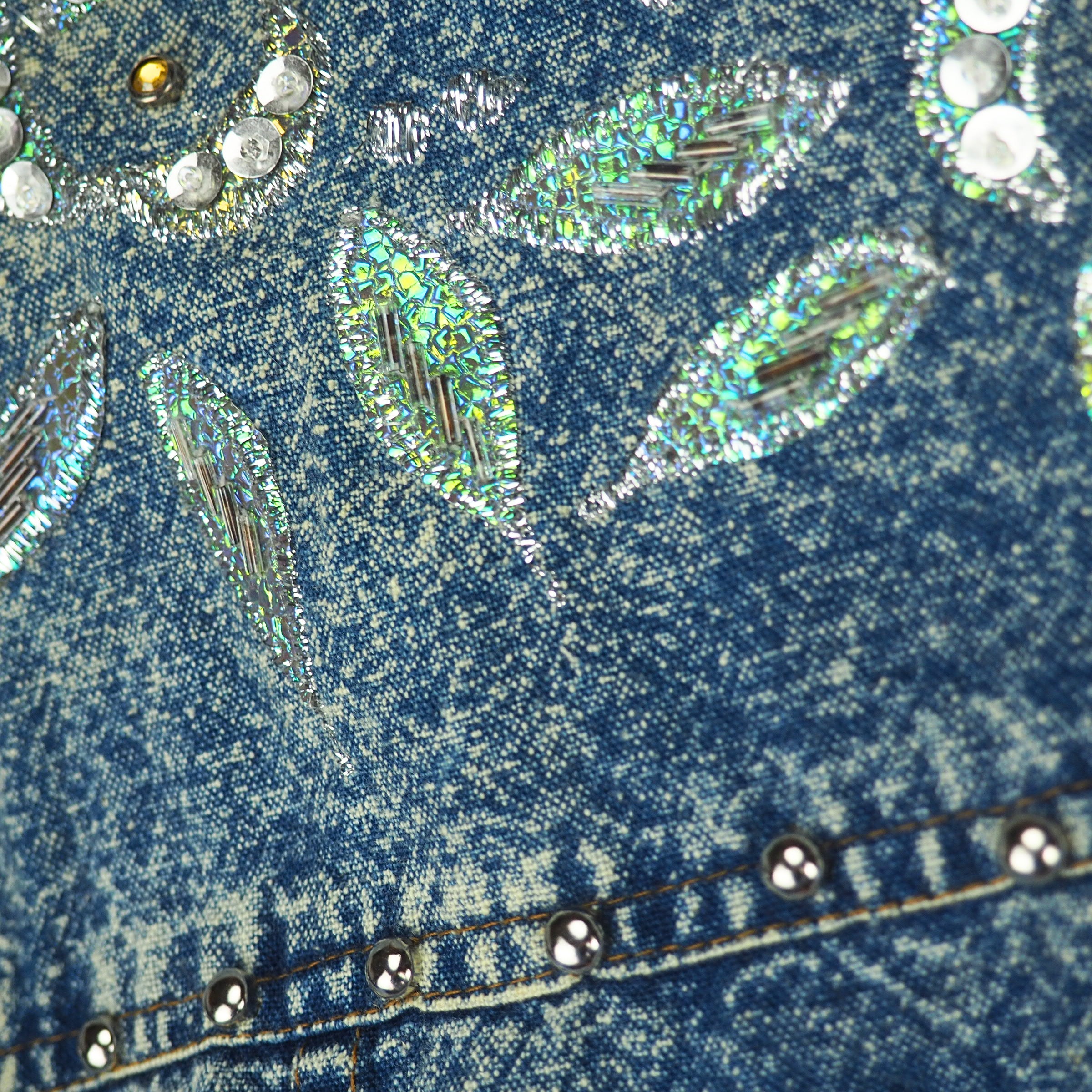 Close-up of blue acid wash denim fabric with decorative elements and rhinestones.
