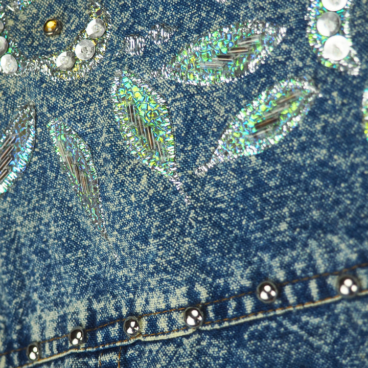 Close-up of blue acid wash denim fabric with decorative elements and rhinestones.