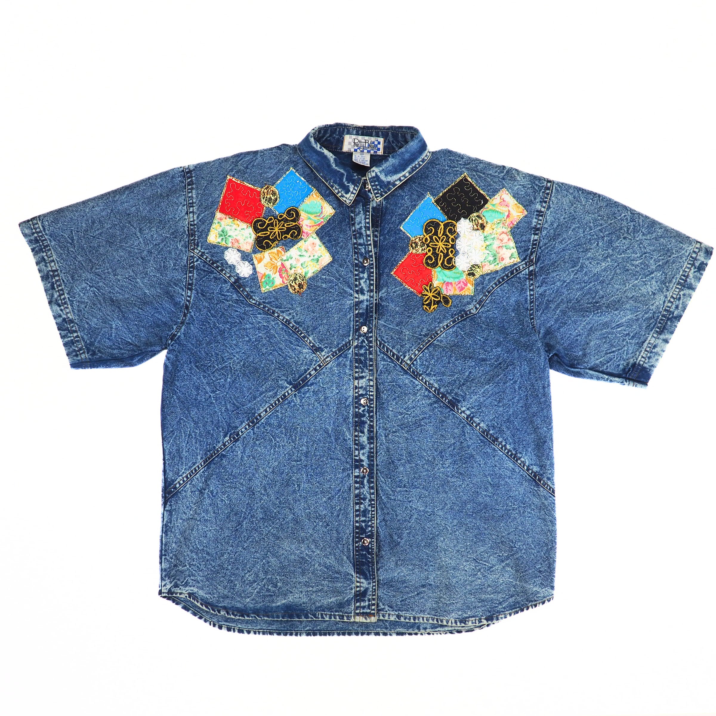 Front view of a 'Pretty Bleu' brand blue acid wash denim shirt with colorful patchwork design on a white background