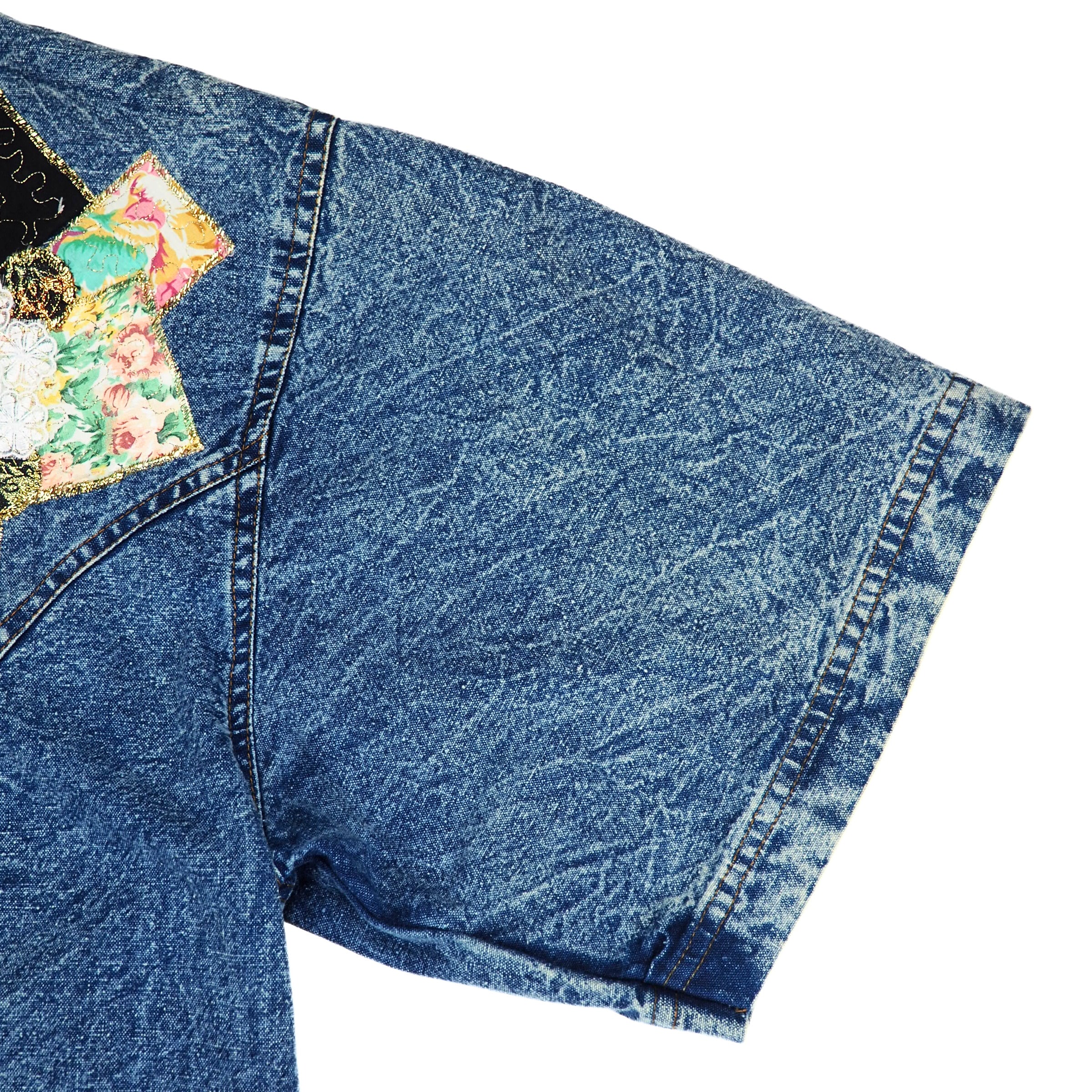 Blue denim shirt sleeve with floral patch on a white background