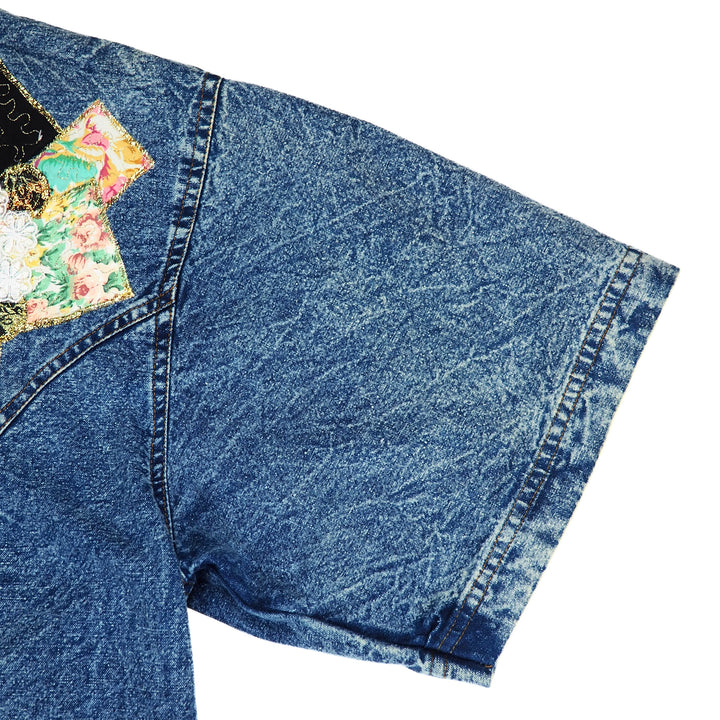 Blue denim shirt sleeve with floral patch on a white background