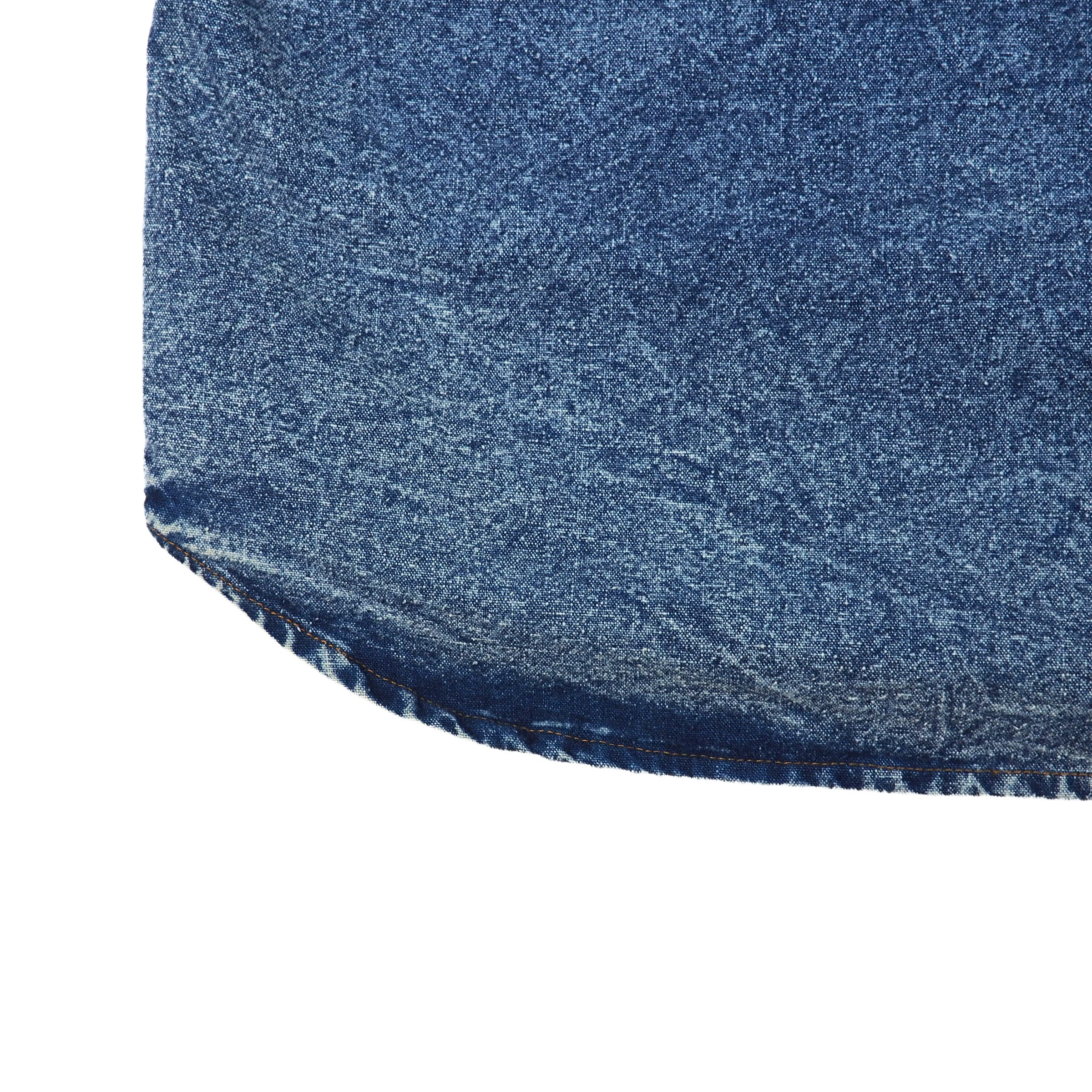 Close-up of a blue denim shirt hem on a white background