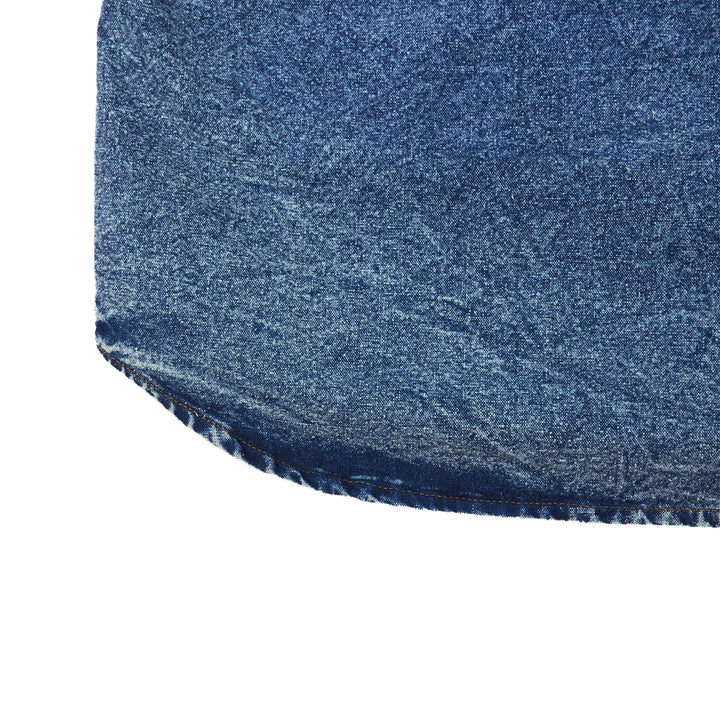 Close-up of a blue denim shirt hem on a white background