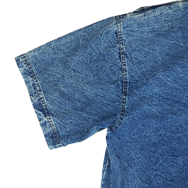 Close-up of a blue denim short sleeved shirt on a white background.