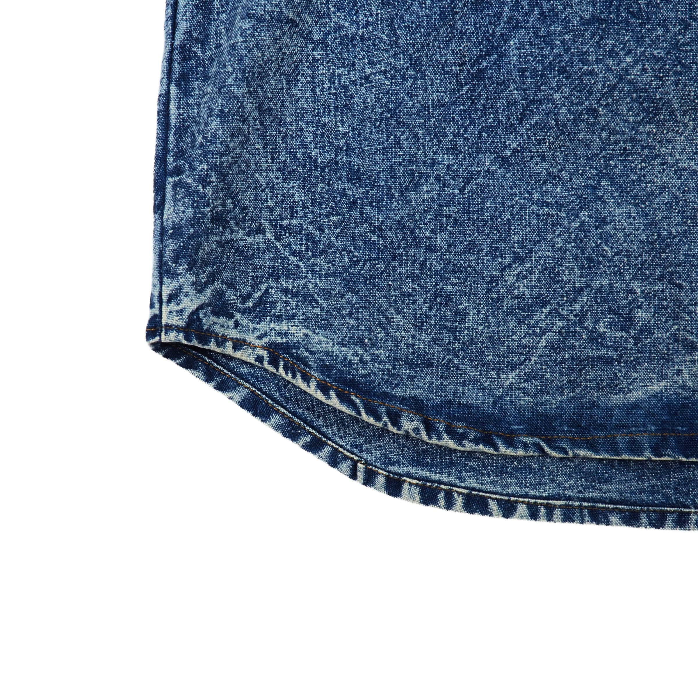 Close-up of blue acid wash denim shirt hem on a white background
