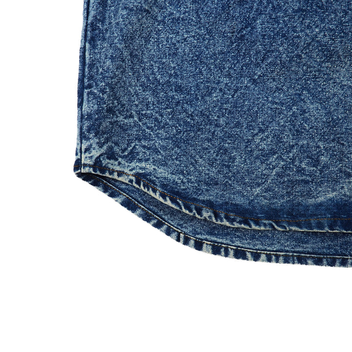Close-up of blue acid wash denim shirt hem on a white background
