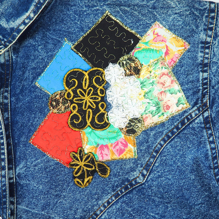 Close-up detail of a vintage denim shirt with colorful patchwork design and embroidery.