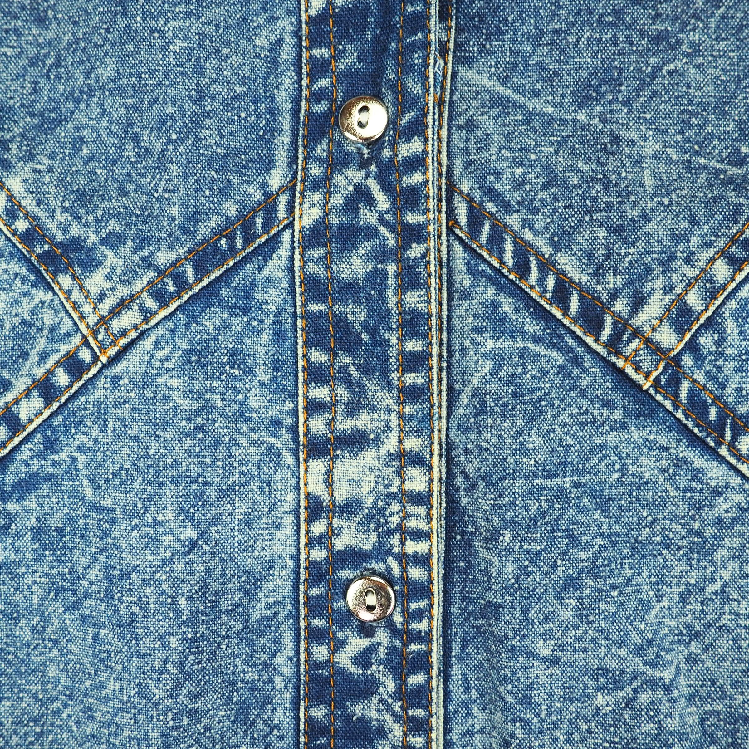 Close-up of a vintage blue acid wash denim shirt with metallic silver button details