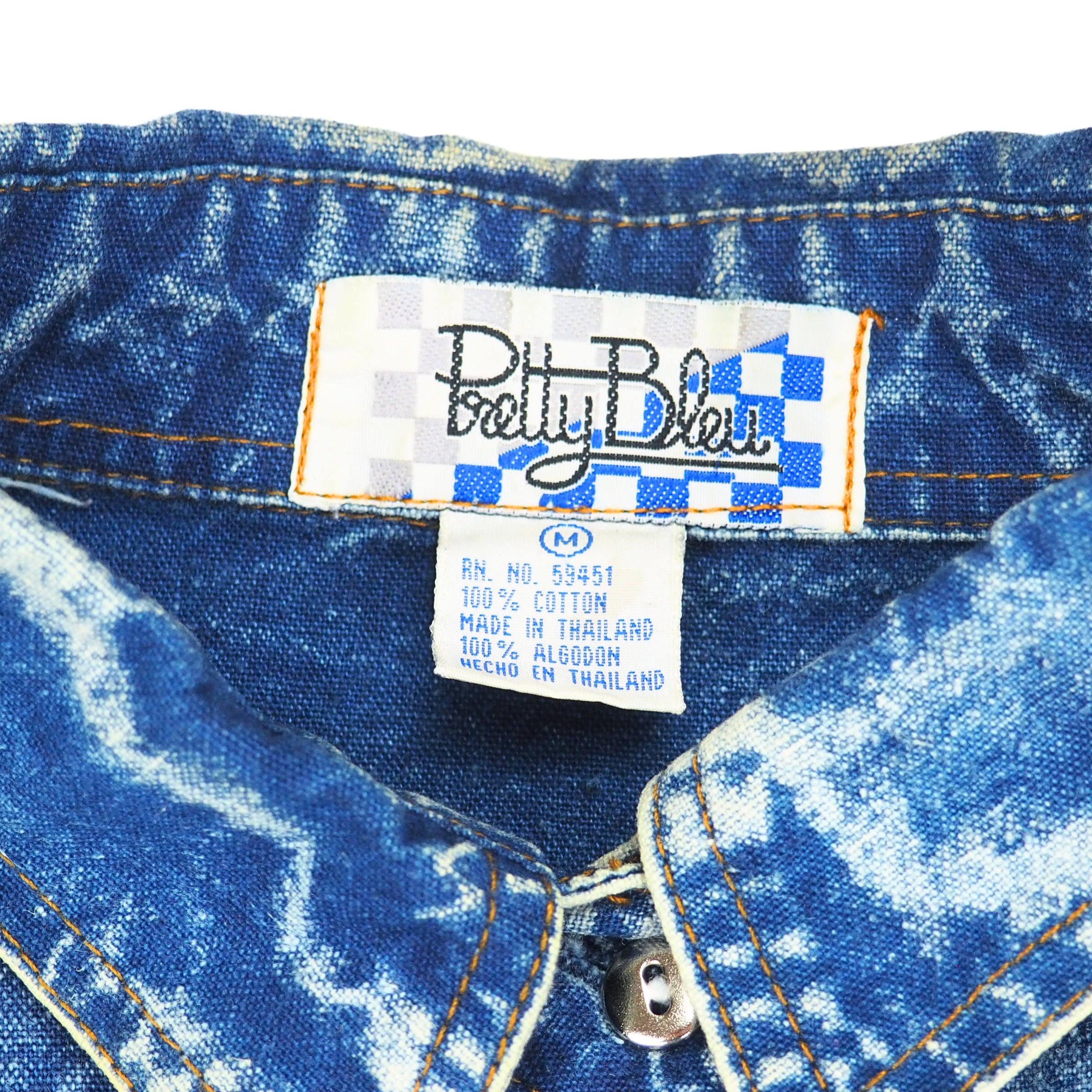 Close-up of a blue denim shirt collar with a 'Pretty Bleu' label.