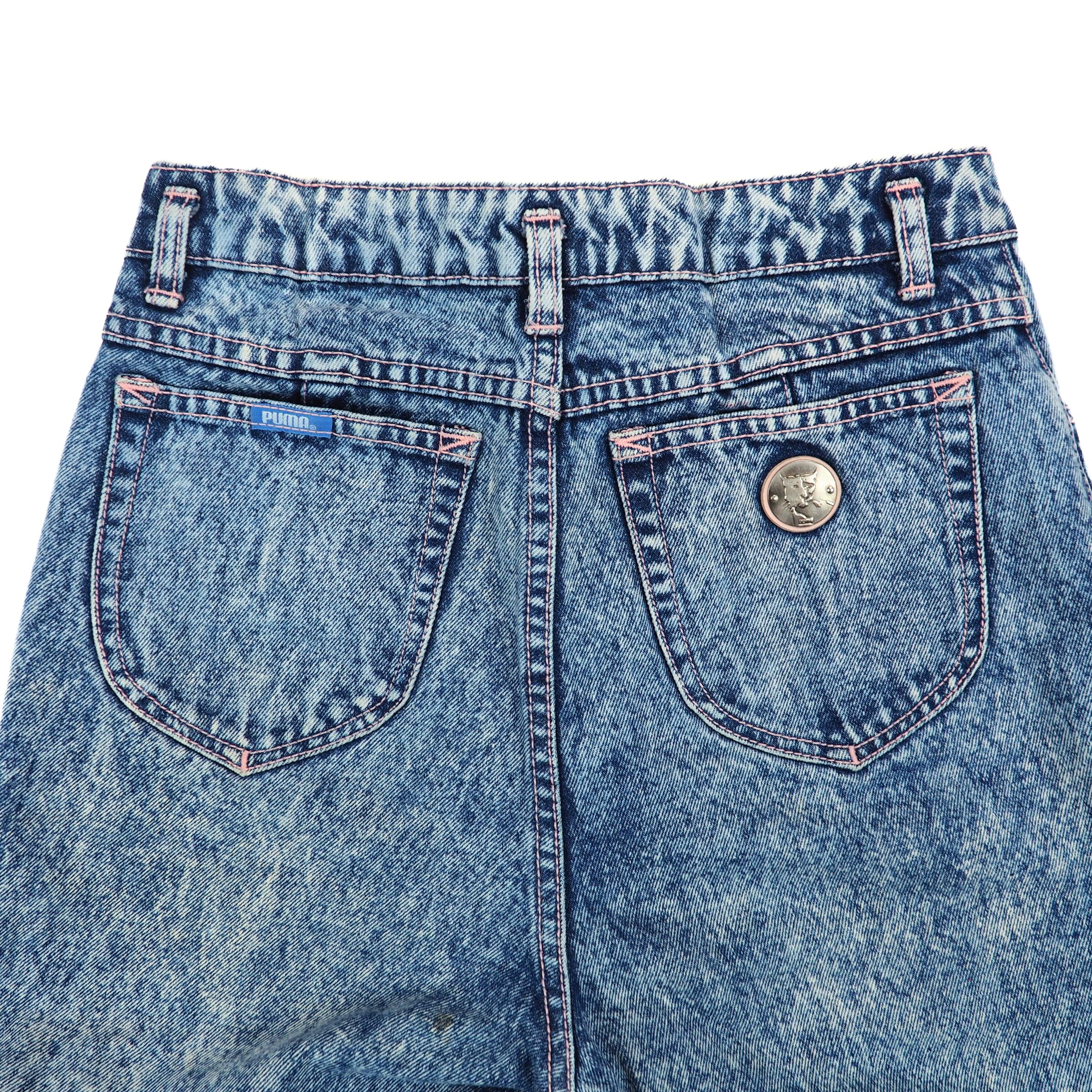 Close-up of the back pockets and waist area of a pair of acid wash jeans on a white background