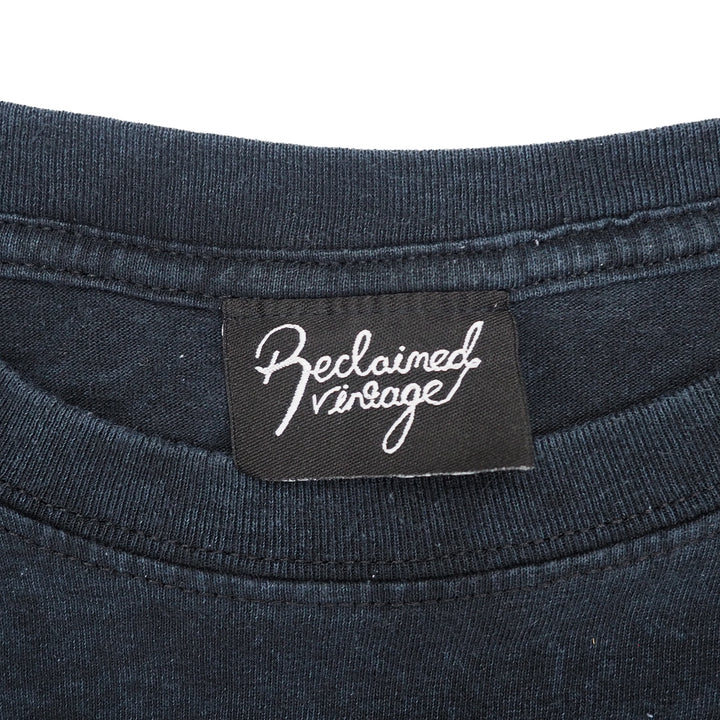 Close up of a black t-shirt with a brand tag on a white background