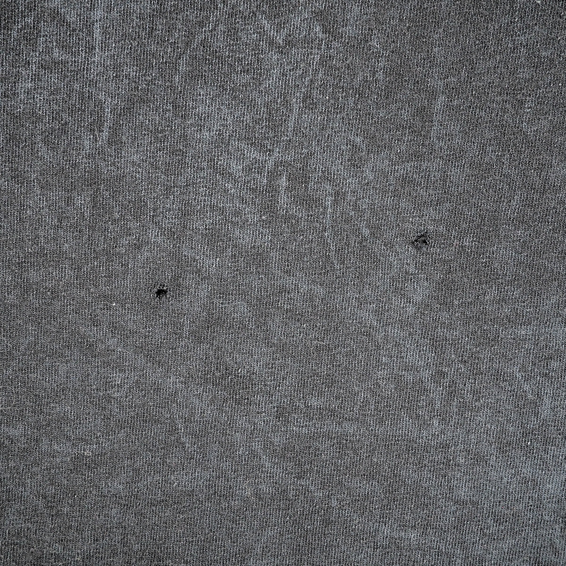 Close up of two small holes in a grey cotton fabric