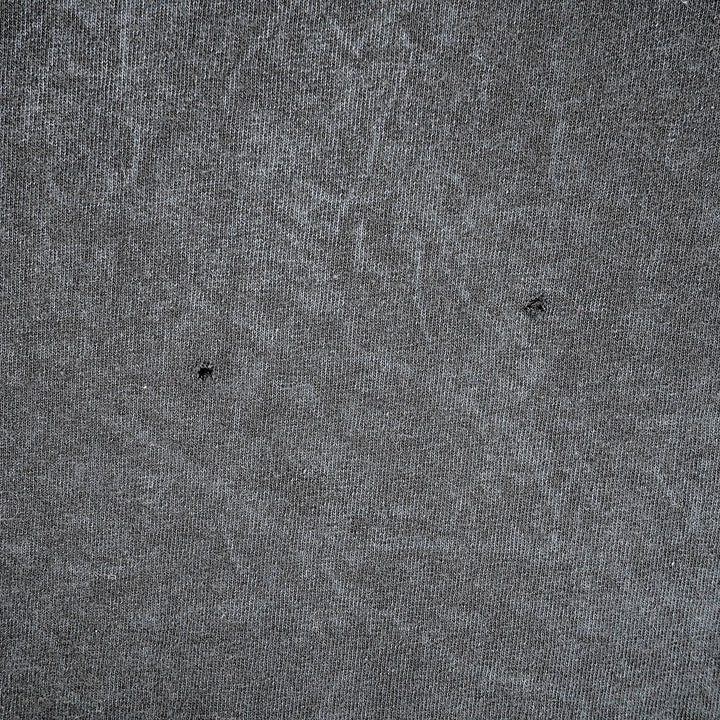 Close up of two small holes in a grey cotton fabric