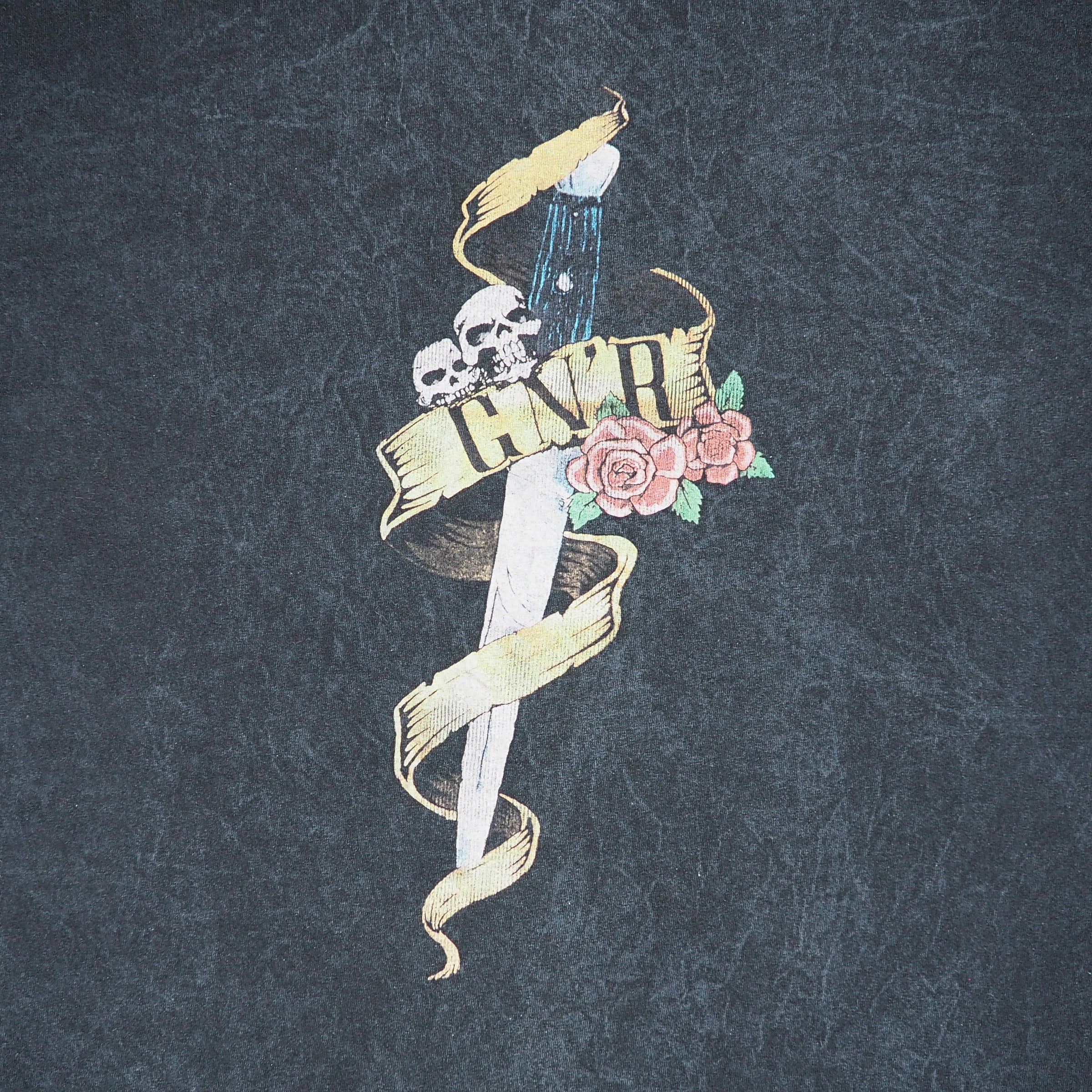 Detail of a 'G n R' dagger logo on a faded black t-shirt