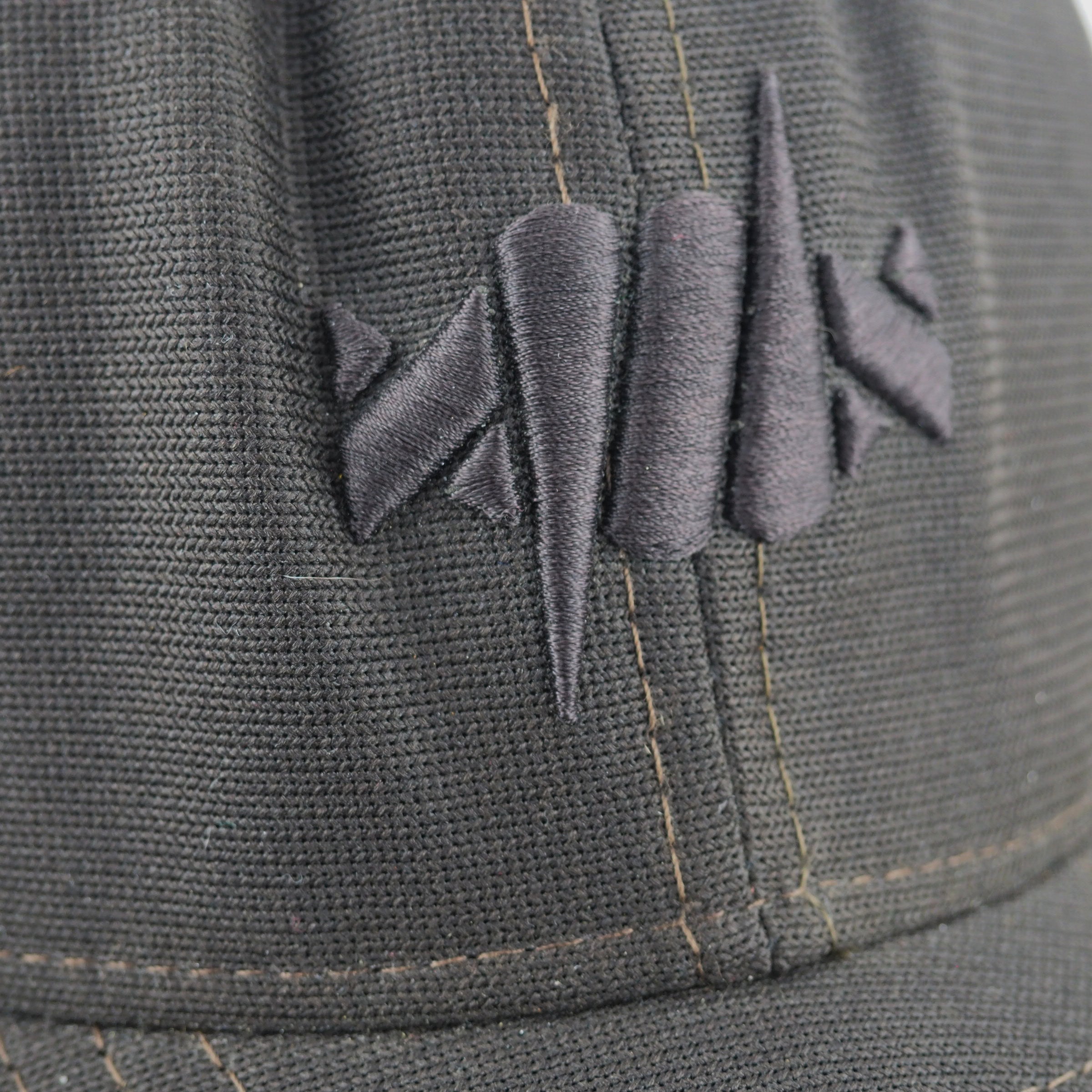 Close-up of a dark gray cap with a barbed wire logo on the front