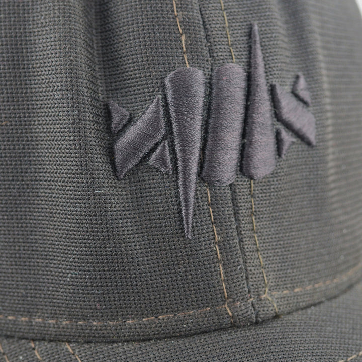 Close-up of a dark gray cap with a barbed wire logo on the front