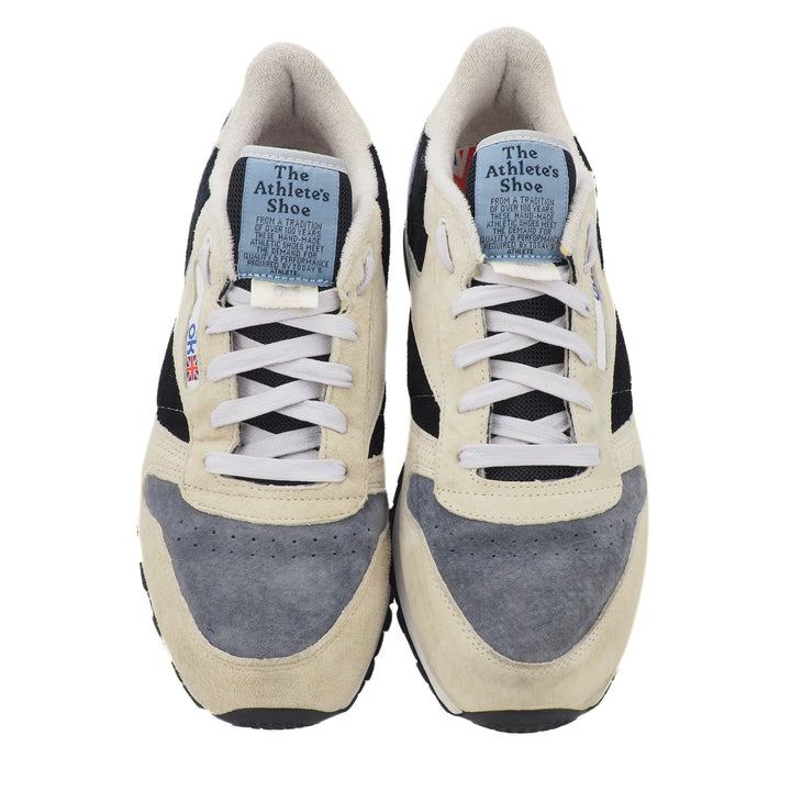 Pair of beige and gray Reebok sneakers with white laces on a white background