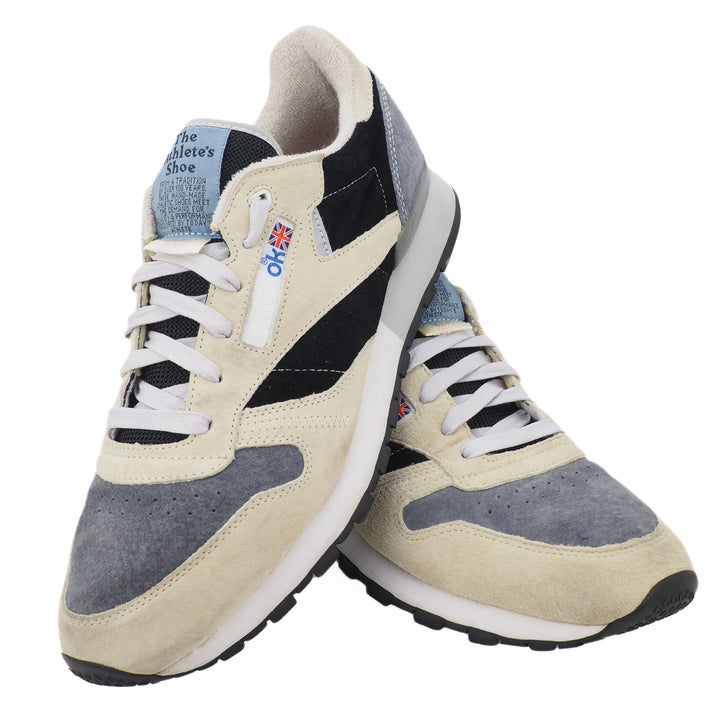 Pair of beige and gray Reebok Classic sneakers with white laces on a white background