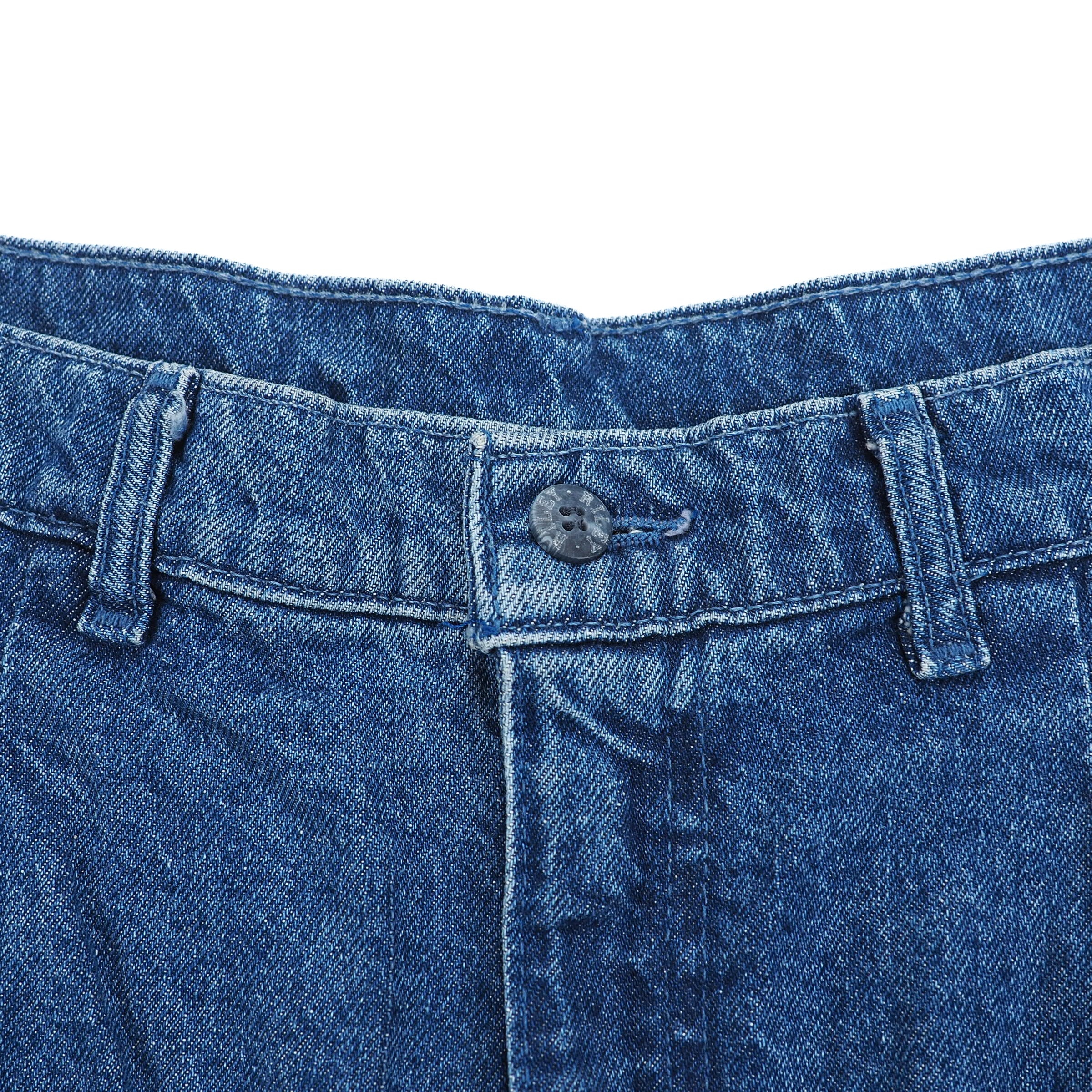 Close-up of blue denim fabric with a button on a white background