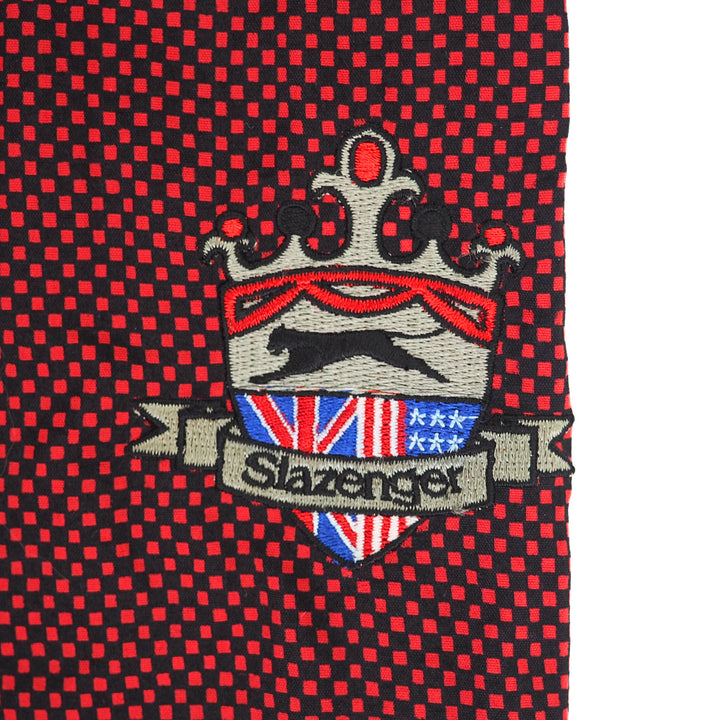 Red and black checkered sweater detail with embroidered logo and text reading Slazenger
