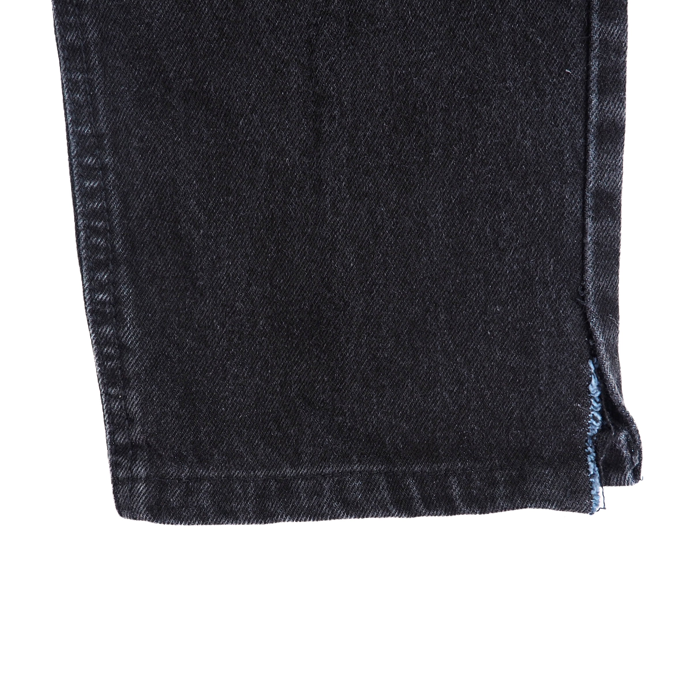 Close-up of black denim jean pants ankle cuff with a white background
