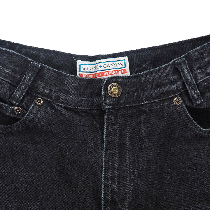 Close-up of black denim jeans waist with a Stone Canyon label on a white background