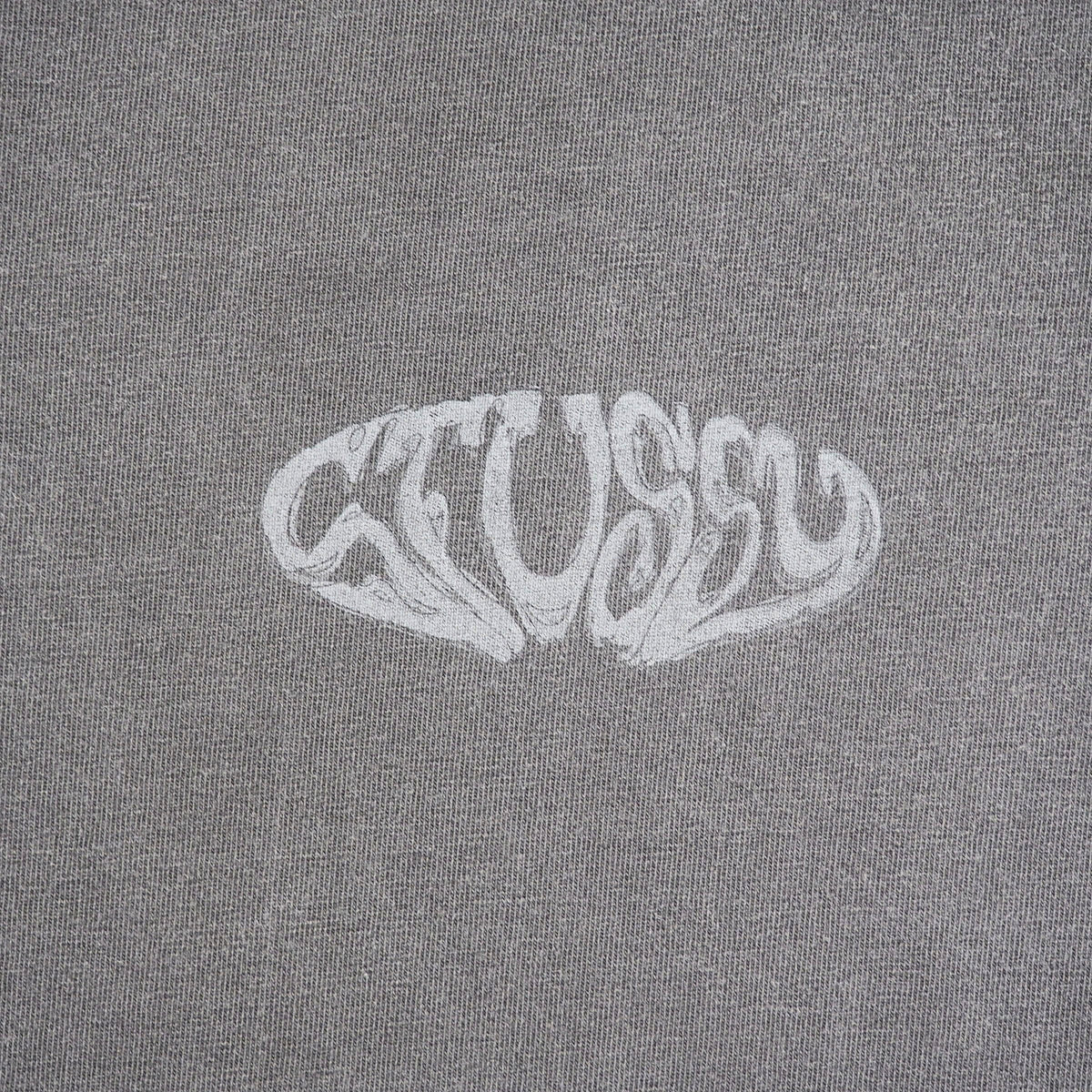 A close-up of a gray heathered fabric with a stylized white 'Stussy' logo printed across the center.