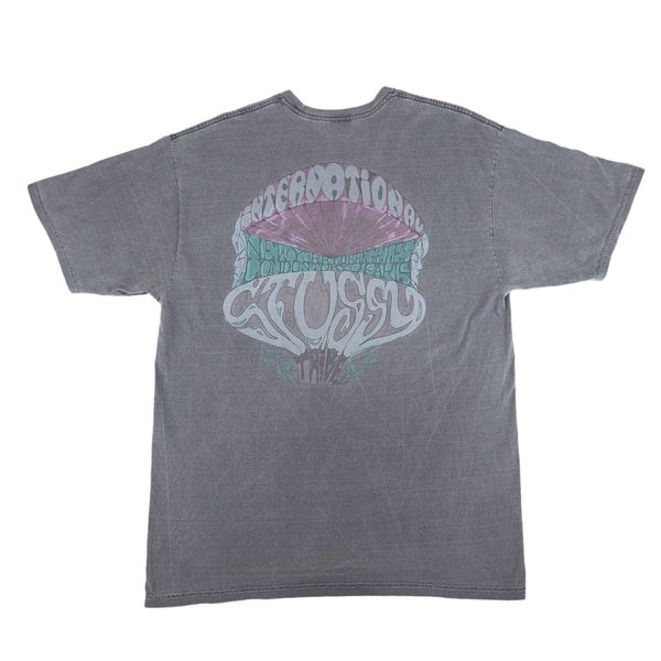 Back view of a washed grey graphic t-shirt by Stussy on a white background.