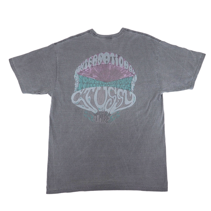 Back view of a washed grey graphic t-shirt by Stussy on a white background.