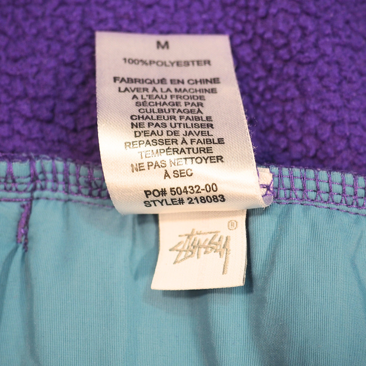 Close up of the inner care tag of a Stussy fleece sweater with style code 218083