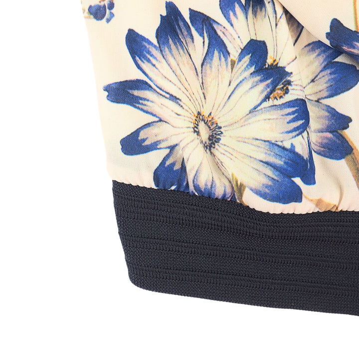 Close-up of a floral-patterned garment with blue and white flowers and black trim on a white background.