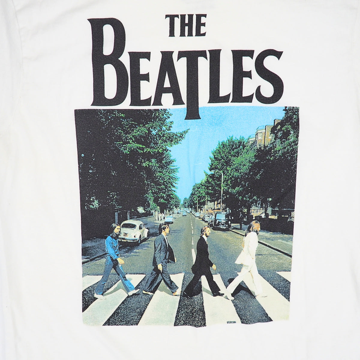 White short-sleeve T-shirt featuring a large front graphic print of The Beatles with the band's name in black above the iconic Abbey Road album cover photo.