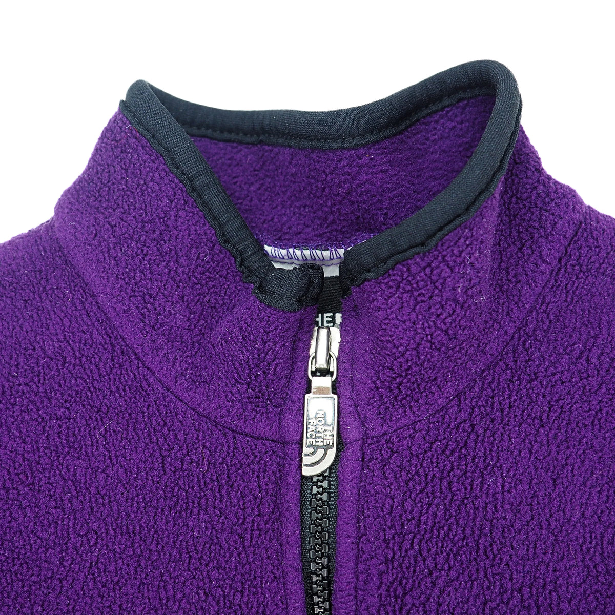 Close up of the collar and zipper of a vintage The North Face fleece vest in purple with black trim on a white background.