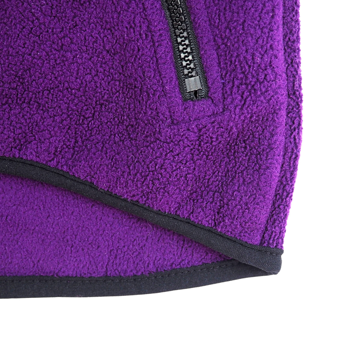 Close up on the black trim and zipper pocket on a purple fleece vest on a white background.