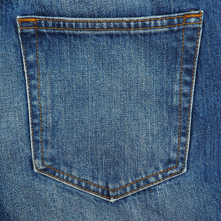 Close-up of a blue denim pocket with orange stitching