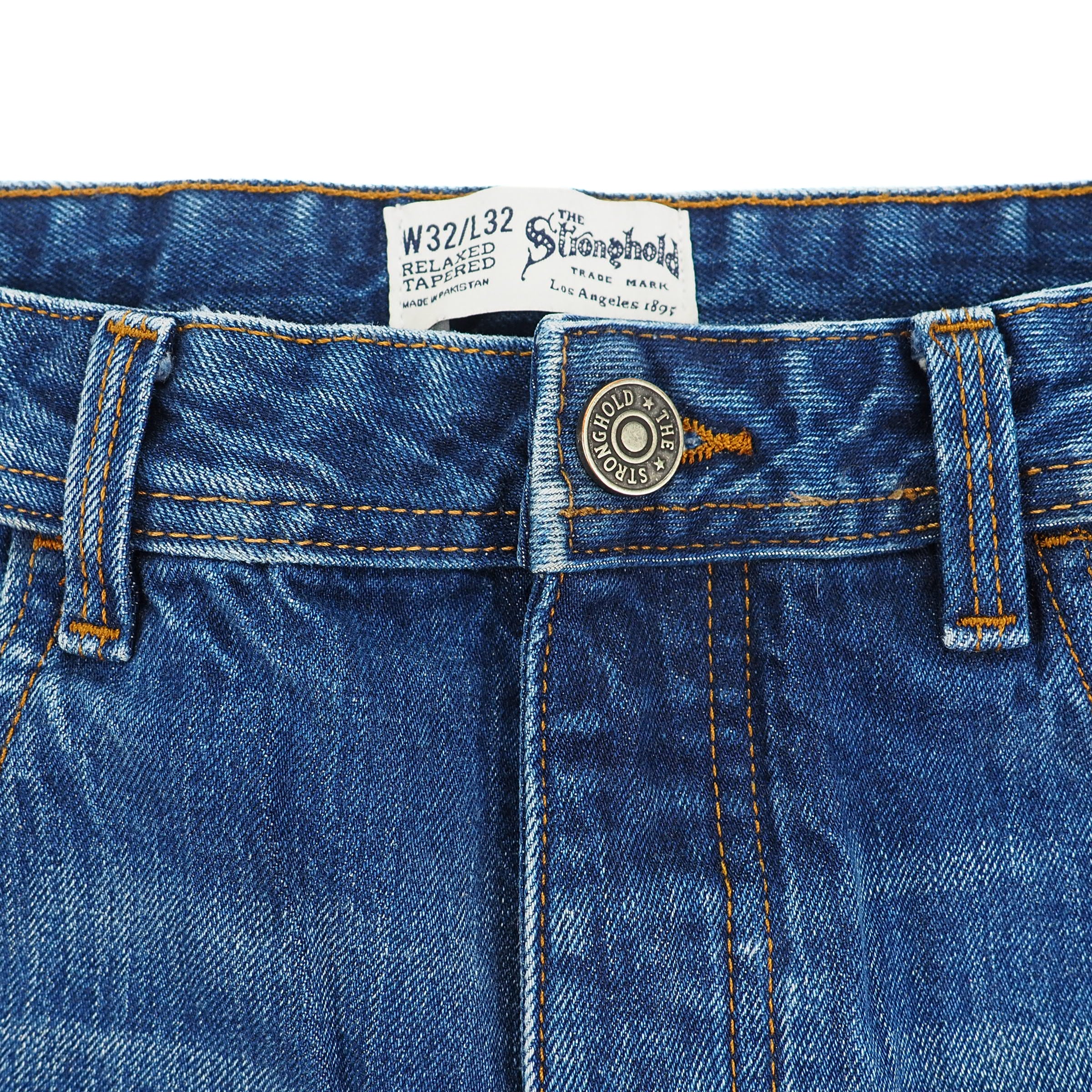 Close-up of blue denim jeans with a button and label on a white background